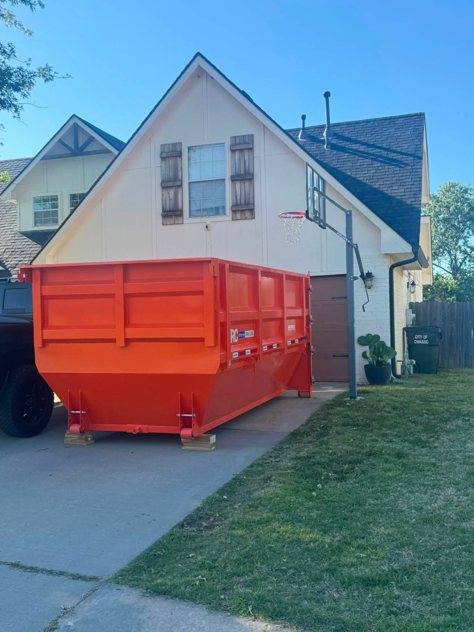 Orange roll-off dumpster placed on a residential driveway in Oklahoma